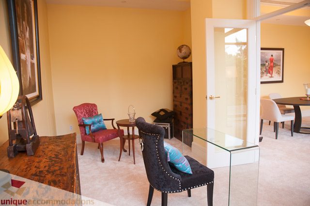 Furnished living room with glass coffee table, armchair, and artwork on the wall. - 103-2288 Bellevue Ave, West Vancouver