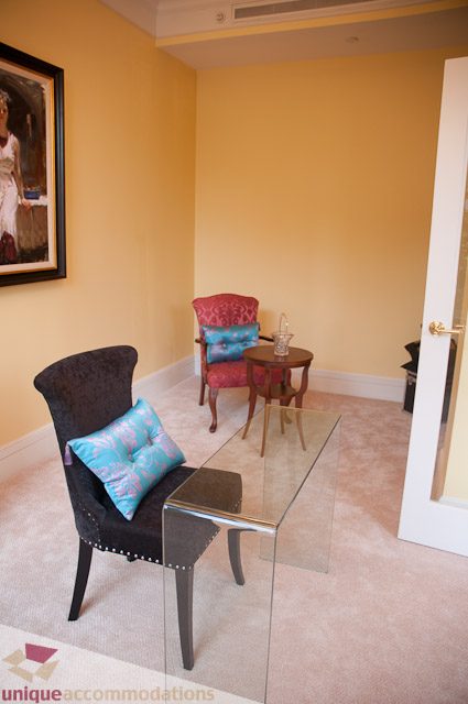 Furnished living room with patterned chairs and a small coffee table. - 103-2288 Bellevue Ave, West Vancouver