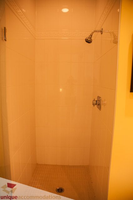 Shower with beige tiles and modern showerhead. - 103-2288 Bellevue Ave, West Vancouver