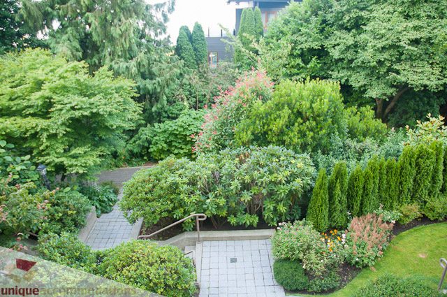 Furnished living room with lush greenery and stone pathways. - 103-2288 Bellevue Ave, West Vancouver