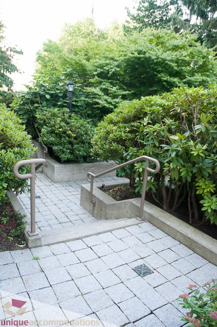 Paved patio with metal railings and lush greenery surrounding. - 103-2288 Bellevue Ave, West Vancouver