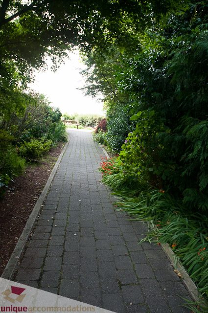 Paved pathway surrounded by lush greenery and vibrant flowers. - 103-2288 Bellevue Ave, West Vancouver