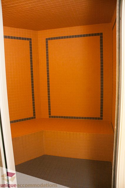 Bathroom with orange tiled walls and black accents. - 103-2288 Bellevue Ave, West Vancouver