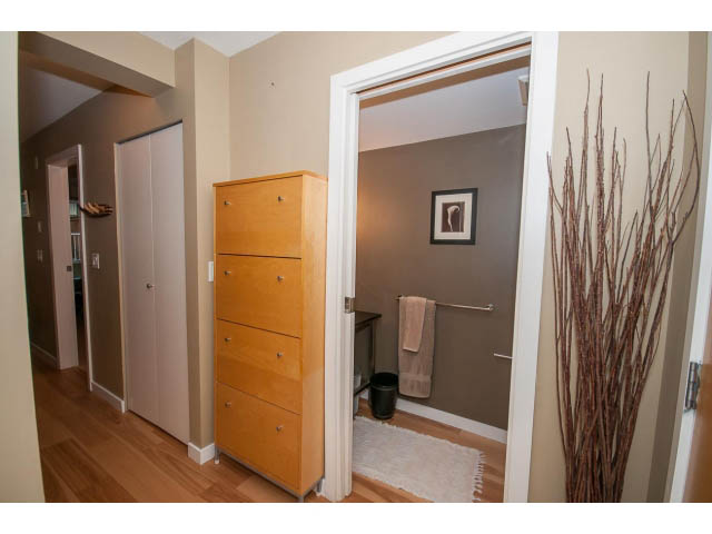 Furnished 1-bedroom + den with wooden floors, light-colored walls, and a small dresser. - 204 - 122 East 3rd Street, North Vancouver