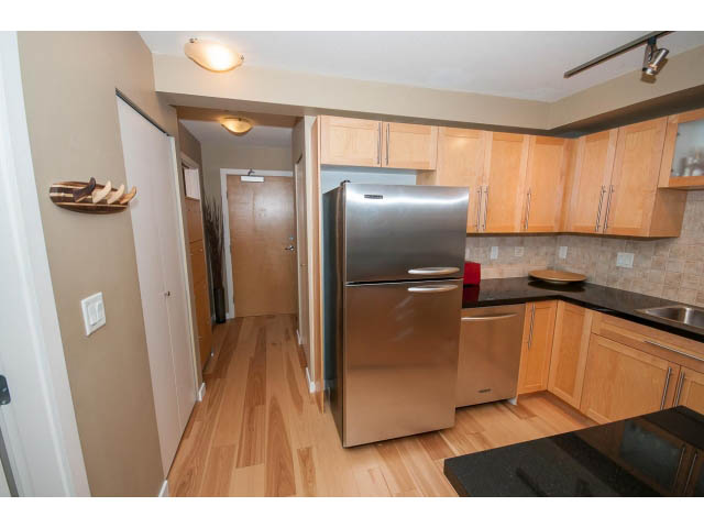Bright kitchen with stainless steel appliances, hardwood floors, and wooden cabinets. - 204 - 122 East 3rd Street, North Vancouver