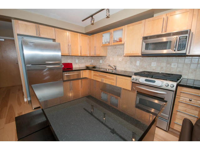 Bright kitchen with granite countertops, stainless steel appliances, and hardwood floors. - 204 - 122 East 3rd Street, North Vancouver