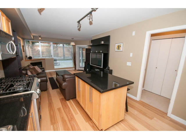 Bright kitchen with black countertops and hardwood floors, city view through large windows. - 204 - 122 East 3rd Street, North Vancouver