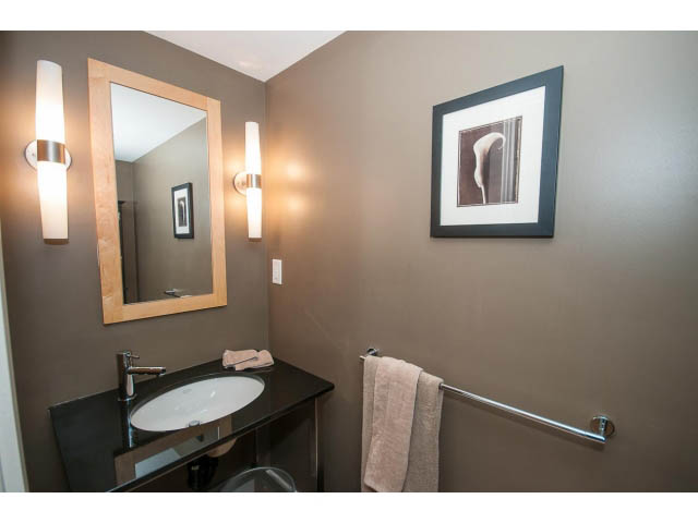 Furnished bathroom with modern sink, wall-mounted mirror, and framed artwork. - 204 - 122 East 3rd Street, North Vancouver