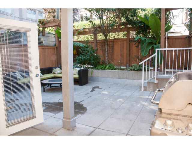 Furnished patio with sliding glass door, wooden fence, and outdoor seating. - 204 - 122 East 3rd Street, North Vancouver