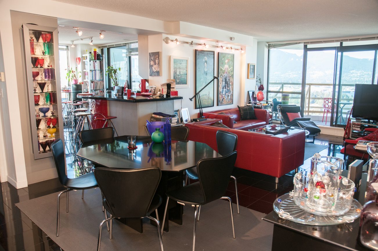 Bright dining and living area with red leather couch, black dining table, and city view. - 3201 - 1331 Alberni, Vancouver Downtown