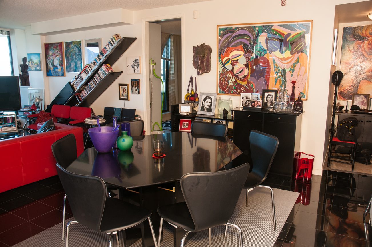 Modern dining area with glossy black table, vibrant red sofa, and colorful artwork. - 3201 - 1331 Alberni, Vancouver Downtown
