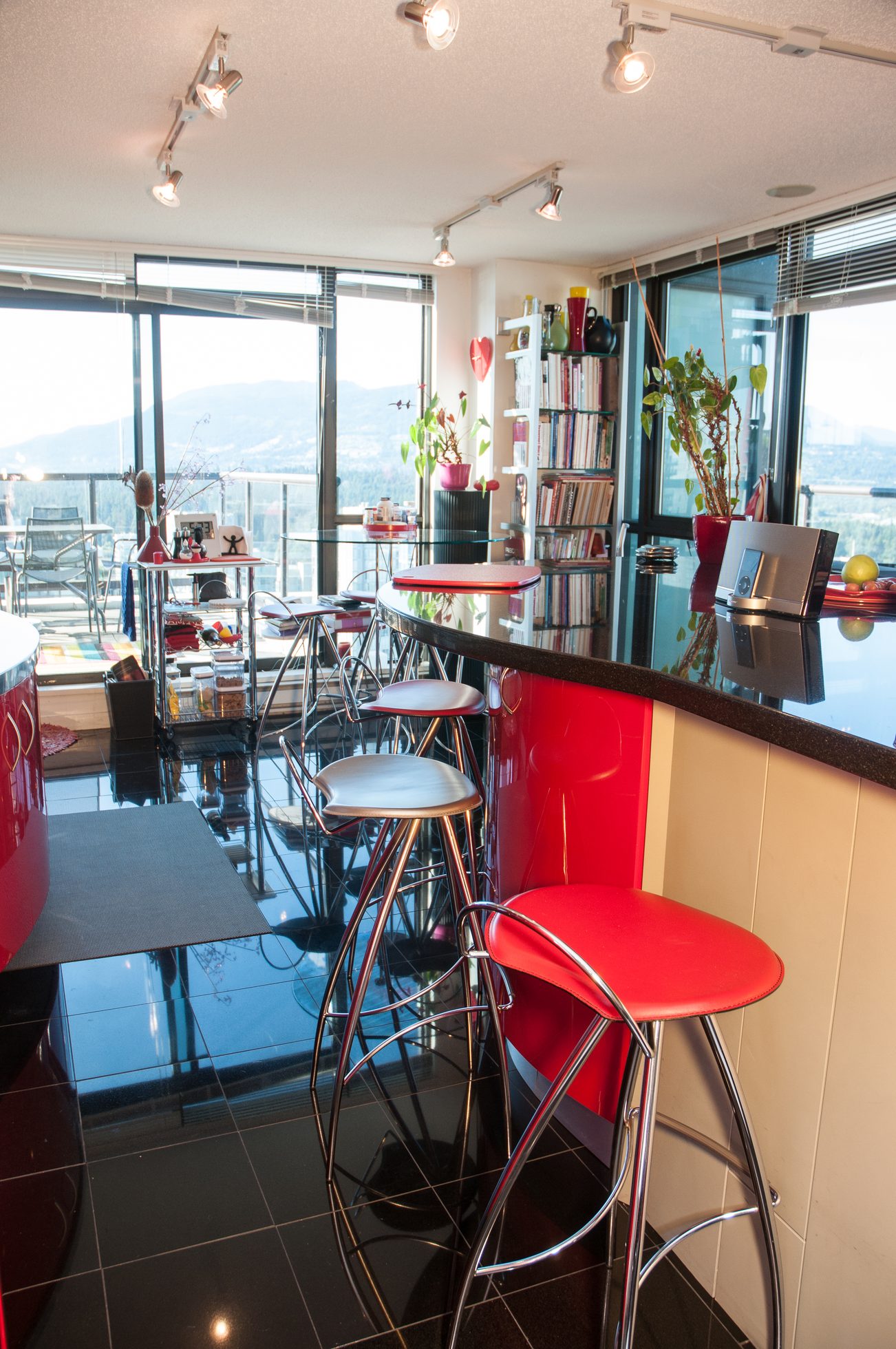 Bright kitchen with red bar stools, city view, and glossy black countertops. - 3201 - 1331 Alberni, Vancouver Downtown