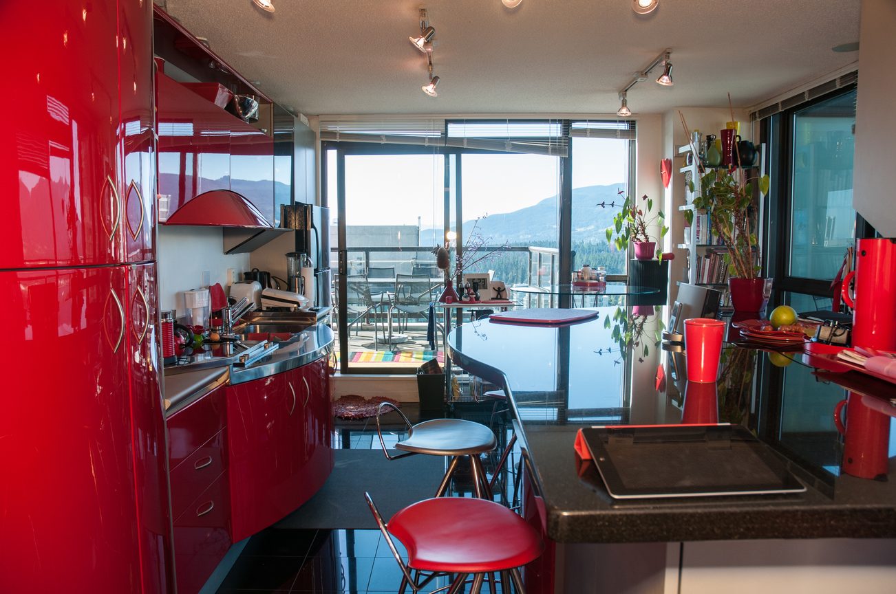 Bright kitchen with glossy red cabinets, city view, and modern bar seating. - 3201 - 1331 Alberni, Vancouver Downtown