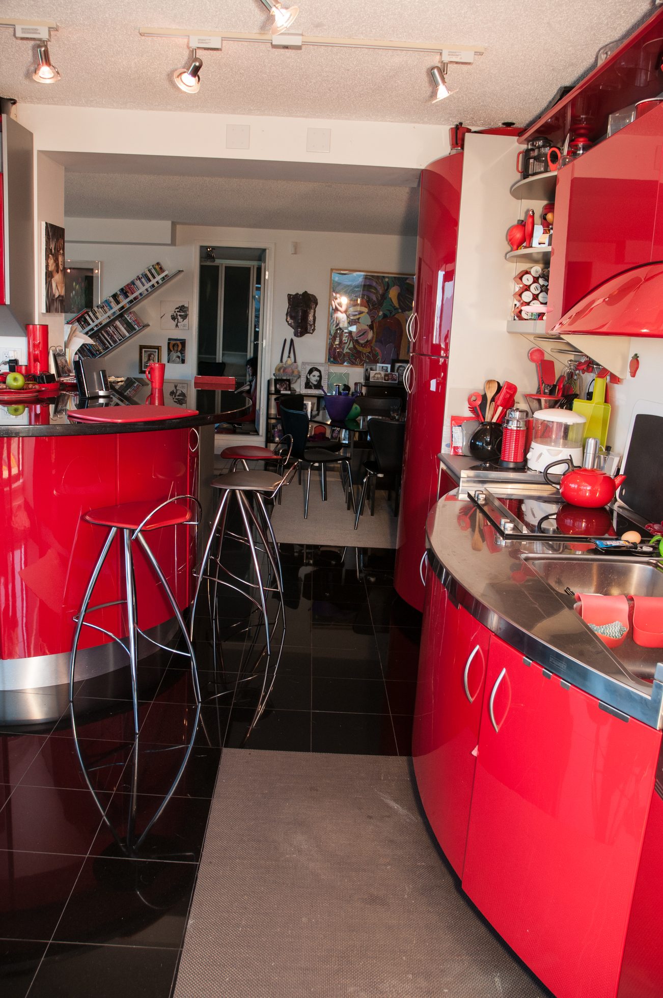 Bright kitchen with red cabinets, black countertops, and a bar area with red stools. - 3201 - 1331 Alberni, Vancouver Downtown