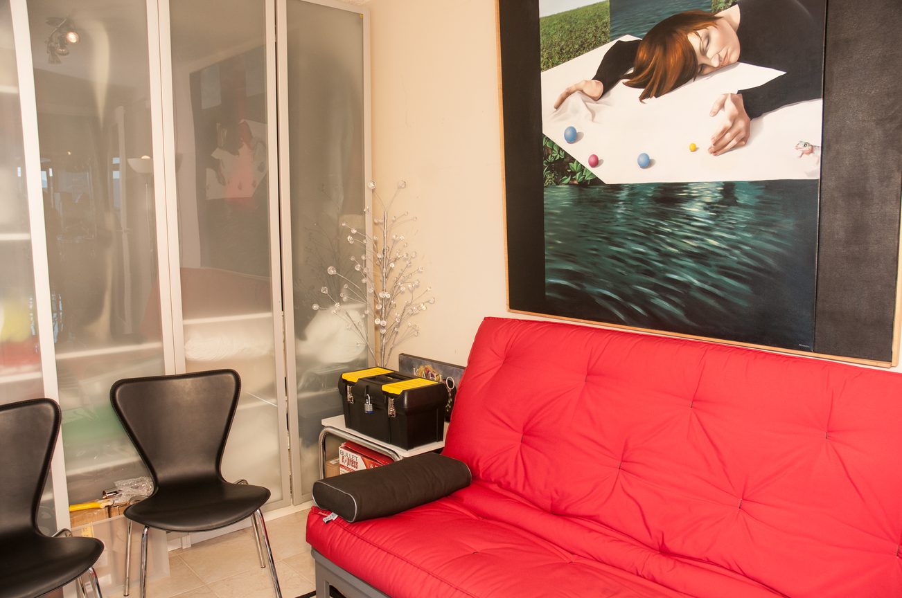 Bright living room with a vibrant red sofa, modern artwork, and glass doors leading to a balcony. - 3201 - 1331 Alberni, Vancouver Downtown