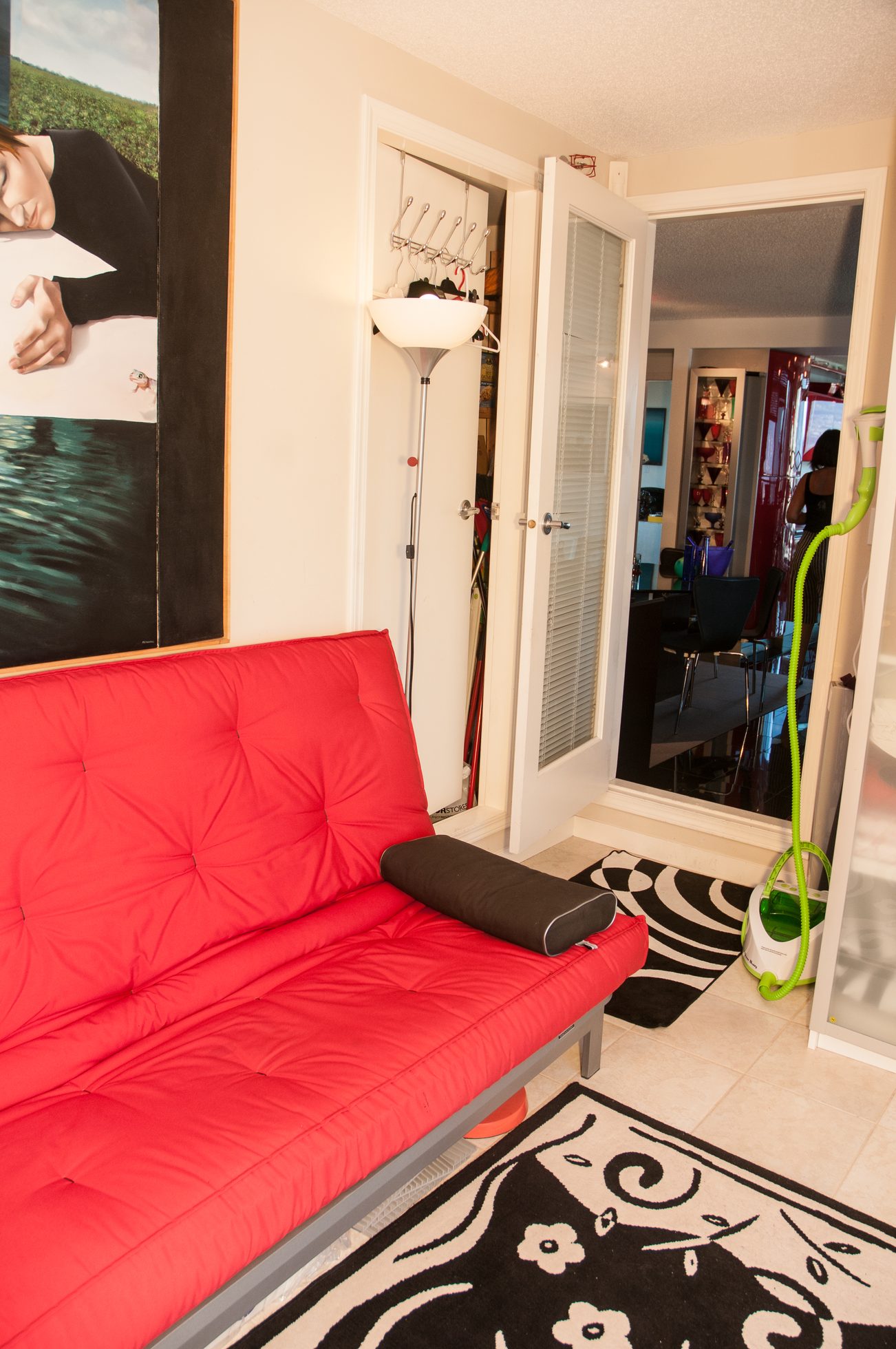 Furnished living room with red futon, black and white rug, and open closet. - 3201 - 1331 Alberni, Vancouver Downtown