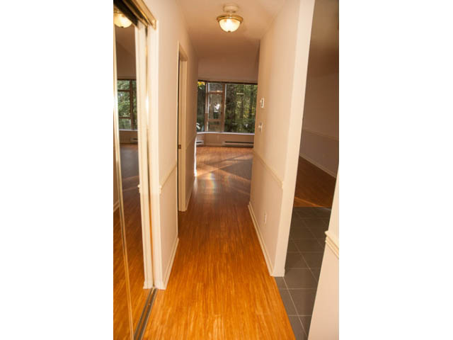 Bright hallway with hardwood floors and sliding glass doors leading to a living area. - 308 - 1327 East Keith Road, North Vancouver