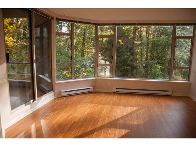 Bright living room with hardwood floors and large windows overlooking trees. - 308 - 1327 East Keith Road, North Vancouver