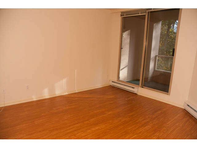 Bright living room with hardwood floors and sliding glass doors leading to a private patio. - 308 - 1327 East Keith Road, North Vancouver