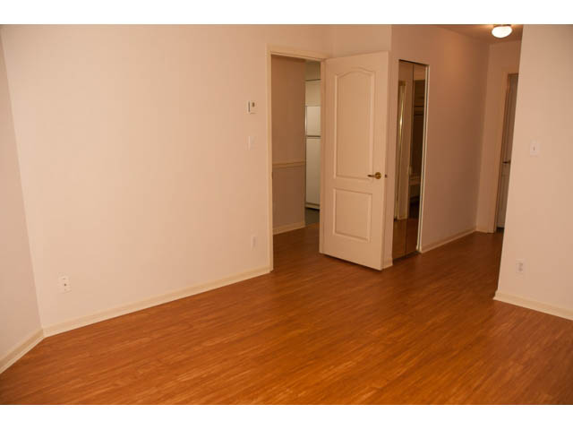Bright living room with hardwood floors and a door leading to another room. - 308 - 1327 East Keith Road, North Vancouver