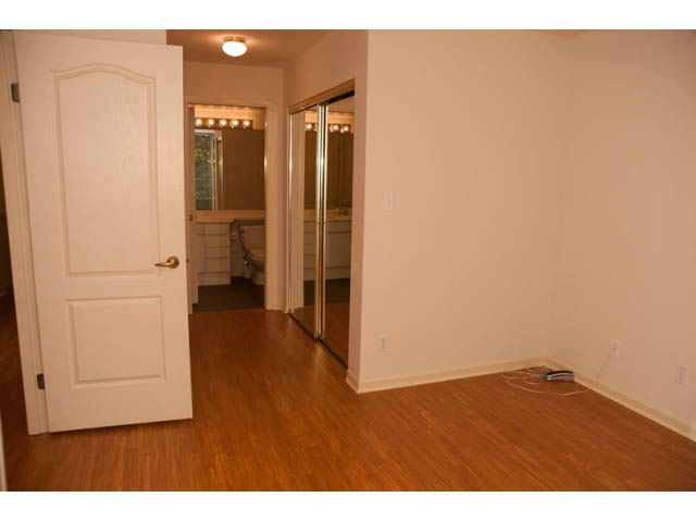 Bright living room with hardwood floors and a sliding glass door leading to a bathroom. - 308 - 1327 East Keith Road, North Vancouver
