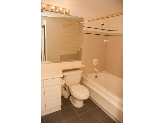 Furnished 1-bedroom condo bathroom with white fixtures and tiled walls. - 308 - 1327 East Keith Road, North Vancouver