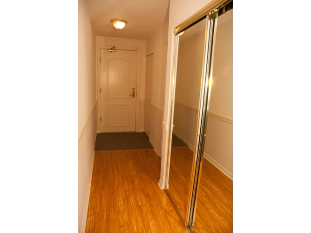 Furnished hallway with hardwood floors and sliding closet doors. - 308 - 1327 East Keith Road, North Vancouver