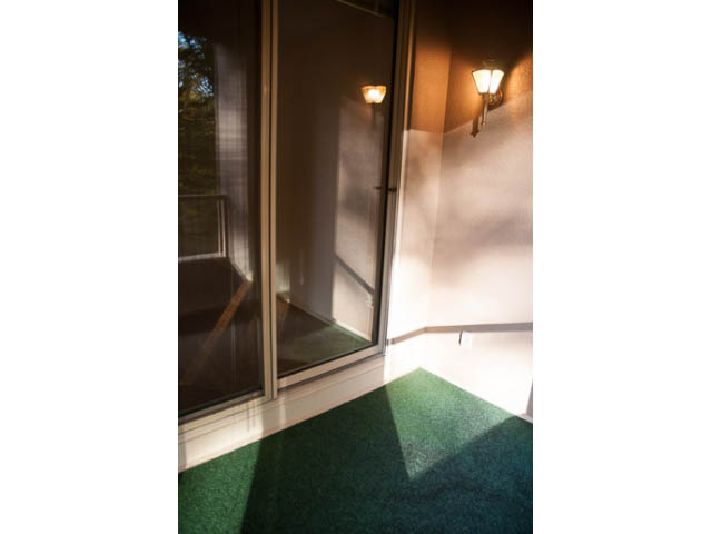 Bright living room with wall sconces and green carpet. - 308 - 1327 East Keith Road, North Vancouver