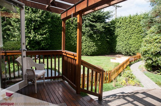 Furnished patio with wooden deck, lush greenery, and a pathway leading to a garden area. - 2885 West 34th Avenue, Vancouver West Side