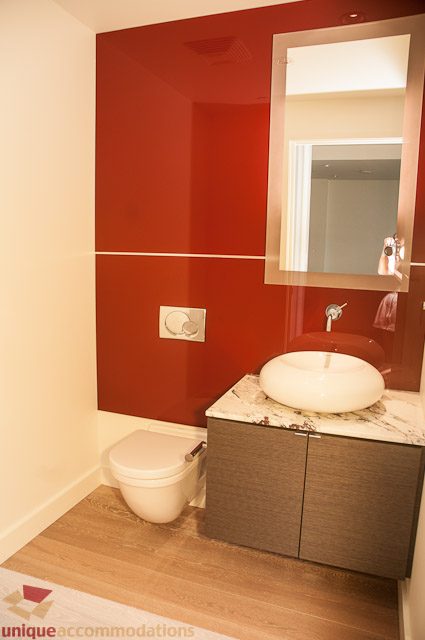 Modern bathroom with red accent wall, white sink, and wooden vanity. - 302 - 1409 W Pender, Vancouver Downtown