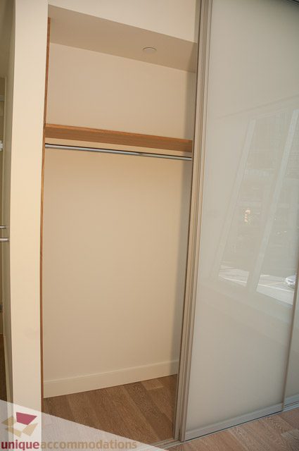 Furnished walk-in closet with sliding glass doors and wooden shelf. - 302 - 1409 W Pender, Vancouver Downtown