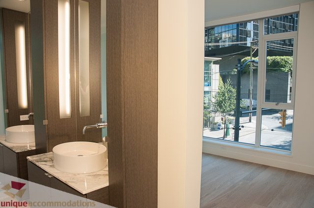 Modern bathroom with sleek countertop and large window offering city views. - 302 - 1409 W Pender, Vancouver Downtown