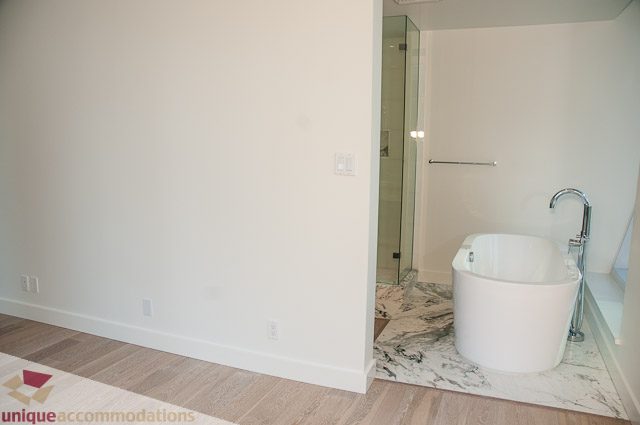 Bright bathroom with white fixtures and marble accents, hardwood floors. - 302 - 1409 W Pender, Vancouver Downtown