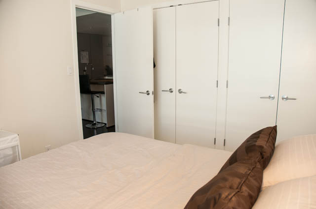 Furnished 1-bedroom with white closet doors and a partially visible bed. - 1504 - 788 Richards, Vancouver Downtown