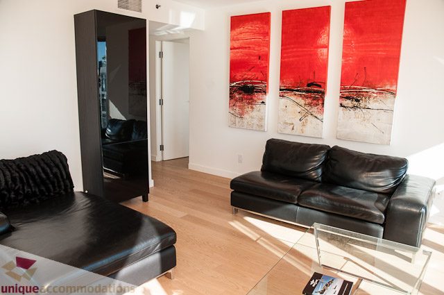Furnished living room with black leather couch, red abstract art, and hardwood floors. - 604-1000 Beach Avenue, Vancouver Downtown