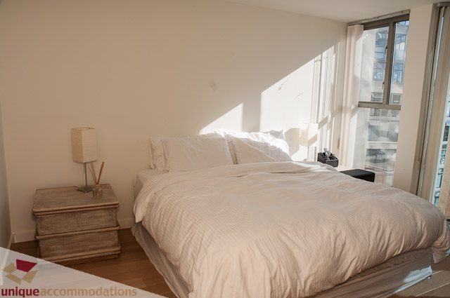 Bright bedroom with natural light, white bedding, and city view. - 604-1000 Beach Avenue, Vancouver Downtown