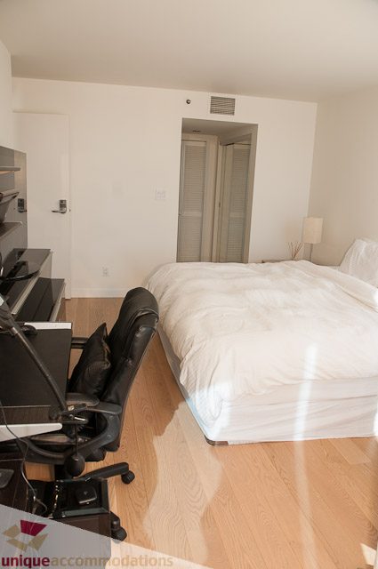 Bright bedroom with hardwood floors and a large bed, featuring a desk and chair setup. - 604-1000 Beach Avenue, Vancouver Downtown