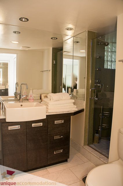 Furnished bathroom with dark wood cabinets, white sink, and glass shower. - 604-1000 Beach Avenue, Vancouver Downtown