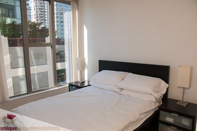 Bright bedroom with large windows, city view, and modern furnishings. - 604-1000 Beach Avenue, Vancouver Downtown