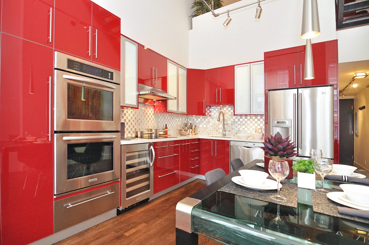 Bright kitchen with red cabinets, stainless steel appliances, and a modern dining table. - PH5- 869 Beatty St., Vancouver Downtown