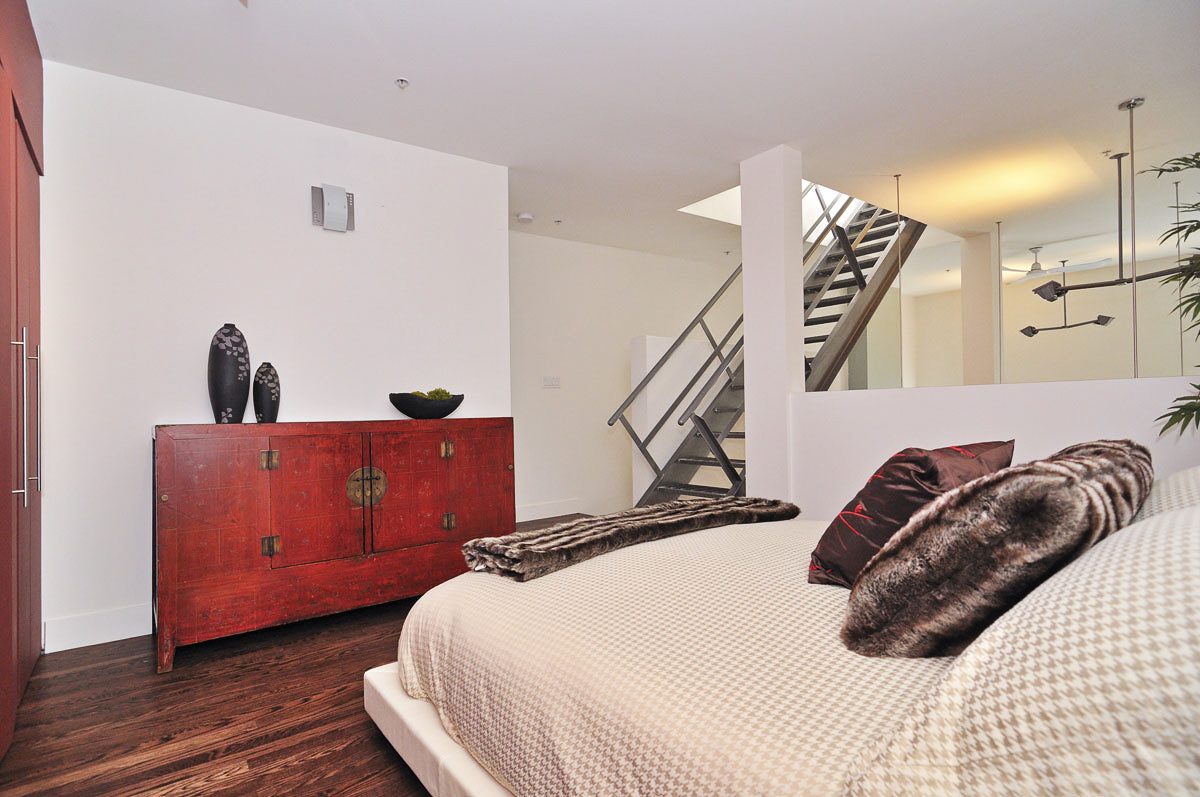 Furnished bedroom with red cabinet, hardwood floors, and a view of the staircase. - PH5- 869 Beatty St., Vancouver Downtown