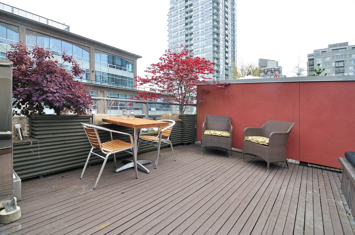 Furnished rooftop patio with wooden deck, wicker chairs, and city views. - PH5- 869 Beatty St., Vancouver Downtown