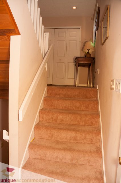 Staircase leading to upper level with carpeted steps and wooden banister. - 4559 W. 3rd Ave, Vancouver West Side