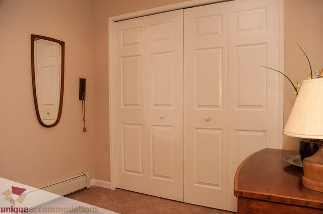 Furnished bedroom with white closet doors and a wooden nightstand. - 4559 W. 3rd Ave, Vancouver West Side