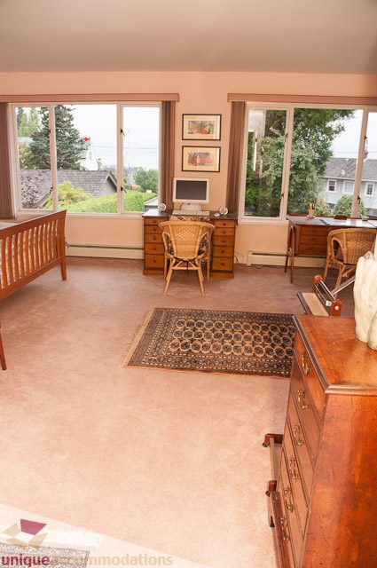 Spacious living room with hardwood floors, large windows, and a cozy corner desk setup. - 4559 W. 3rd Ave, Vancouver West Side