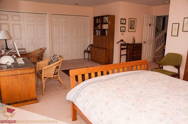 Furnished living room with wooden furniture and a desk, leading to a staircase. - 4559 W. 3rd Ave, Vancouver West Side