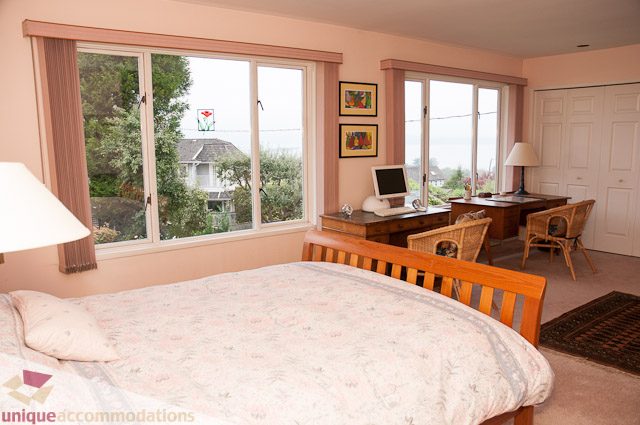 Bright bedroom with large windows, city view, and wooden furniture. - 4559 W. 3rd Ave, Vancouver West Side