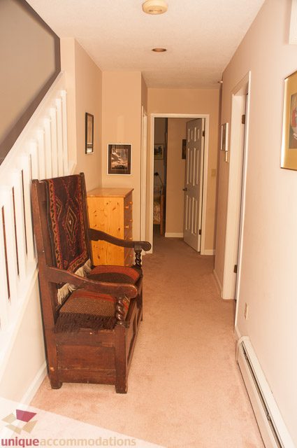 Furnished hallway with wooden chair and dresser, leading to bedrooms. - 4559 W. 3rd Ave, Vancouver West Side
