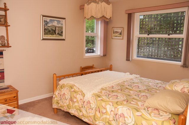 Bright bedroom with floral bedding and large windows, letting in natural light. - 4559 W. 3rd Ave, Vancouver West Side