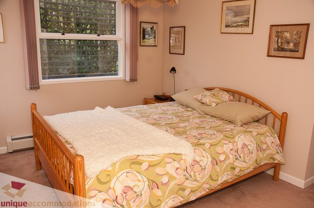 Bright bedroom with floral bedding and framed artwork on the wall. - 4559 W. 3rd Ave, Vancouver West Side